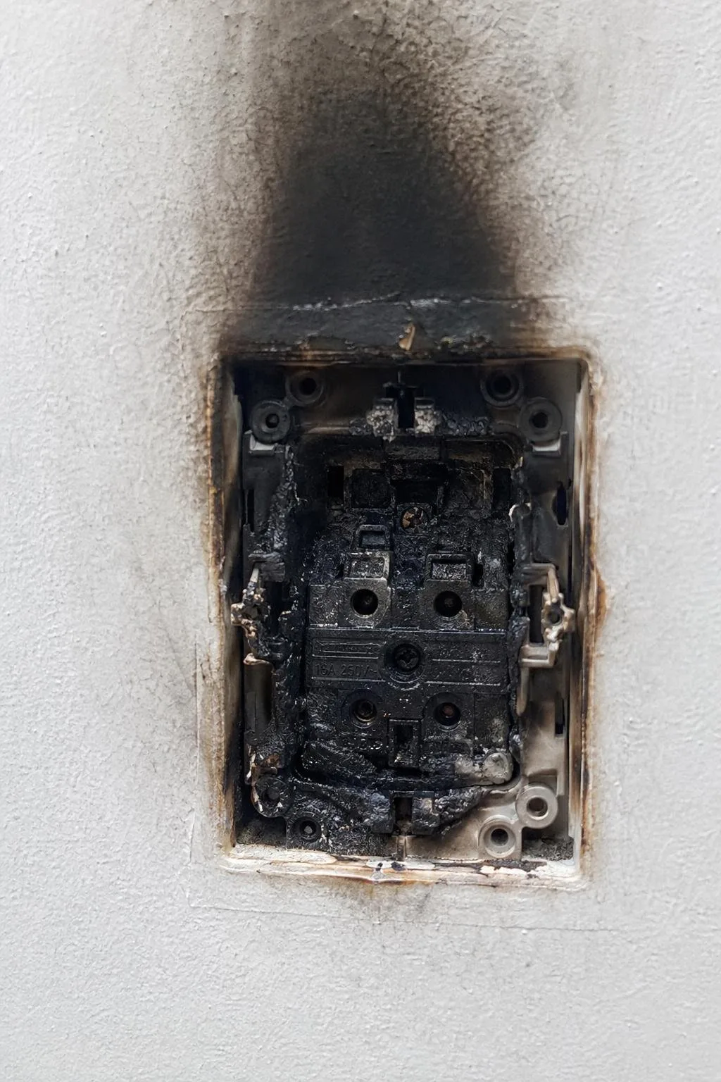 Enchufe quemado con la tapa retirada en una vivienda